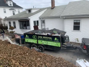 A truck and trailer from "Junk Removal & Hauling LCC" filled with discarded items